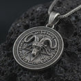 Load image into Gallery viewer, Oxidized Baphomet pendant necklace on textured volcanic rock, close-up studio shot highlighting the goat head relief, pentagram background, occult sigils, and antique silver contrast.
