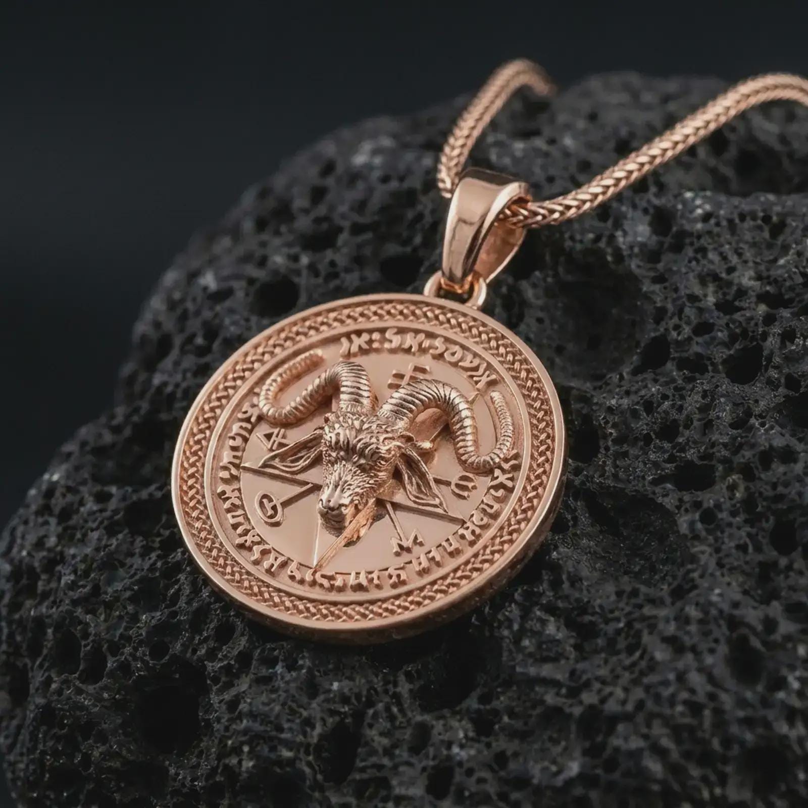 Rose gold plated Baphomet pendant necklace on textured volcanic rock, detailed macro product shot with soft warm reflections and gothic ritual symbolism.