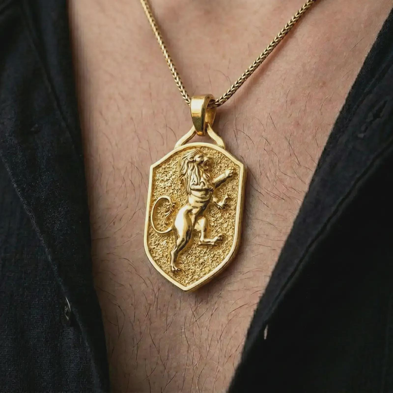 Gold plated heraldic lion shield pendant necklace worn on the chest, premium lifestyle jewelry photo with the royal lion shield pendant centered on a spiga chain.