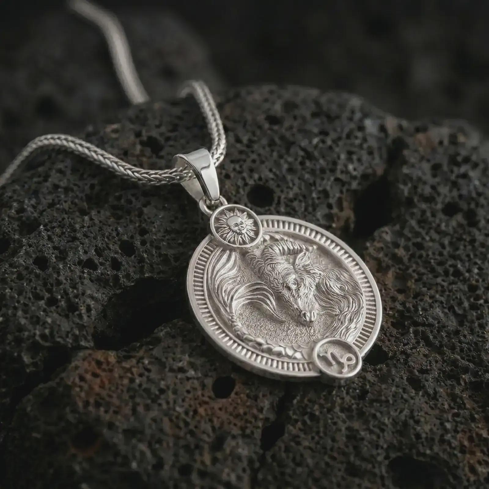 Polished silver Capricorn zodiac pendant necklace on textured volcanic rock, centered macro jewelry photo with detailed sea goat horoscope relief and bright silver highlights.