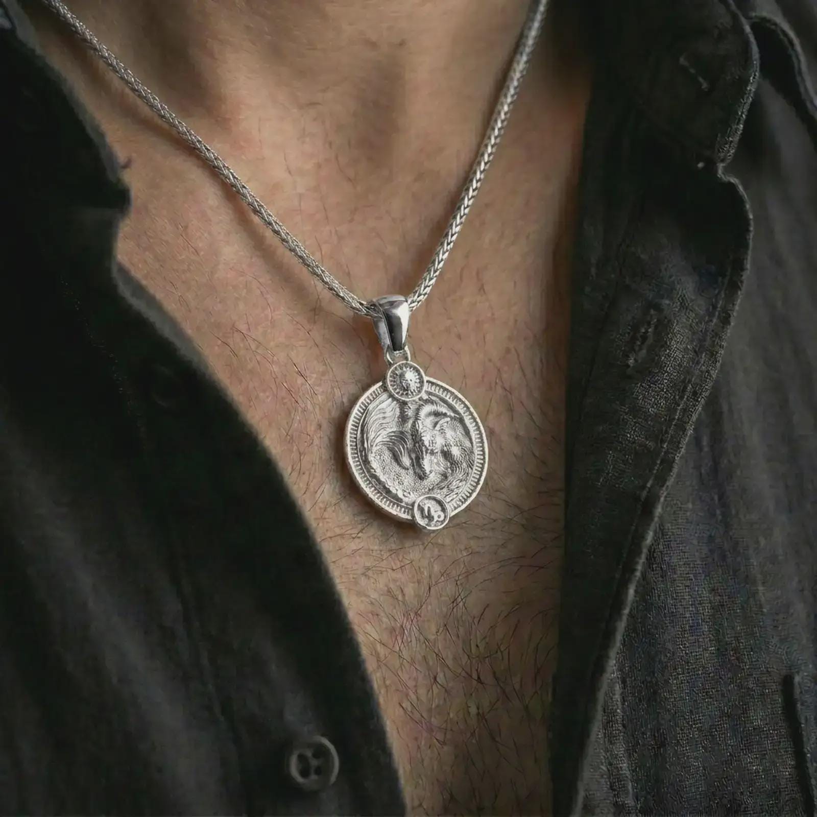 Polished silver Capricorn zodiac pendant necklace worn on the chest, masculine lifestyle shot highlighting the sea goat relief, sun detail, and bright silver finish.