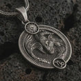Load image into Gallery viewer, Oxidized Capricorn zodiac pendant necklace on textured volcanic rock, close-up studio shot highlighting the sea goat relief, sun detail, Capricorn symbol, and antique silver contrast.
