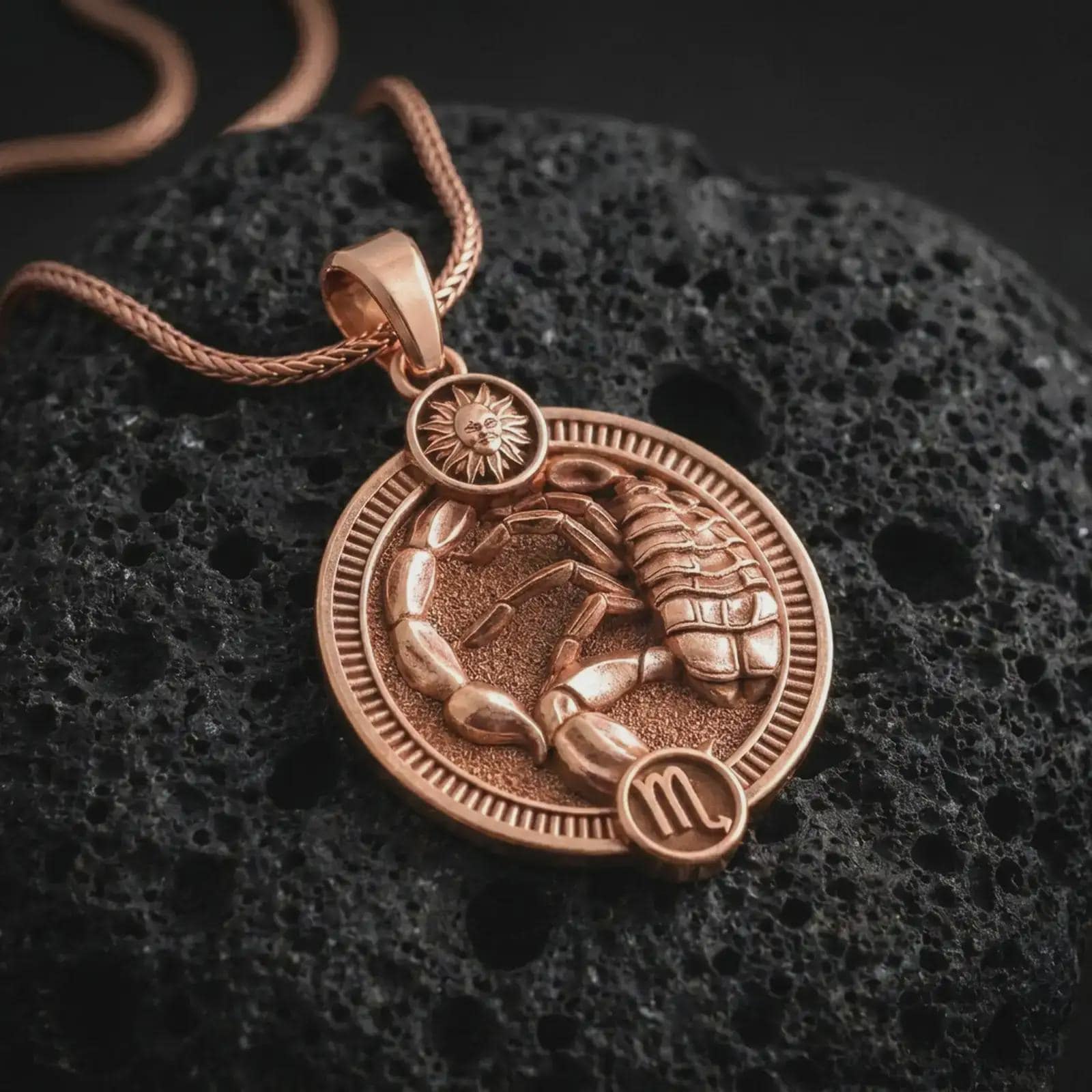 Rose gold plated Scorpio zodiac pendant necklace on textured volcanic rock, detailed macro product shot with soft warm reflections and symbolic zodiac styling.