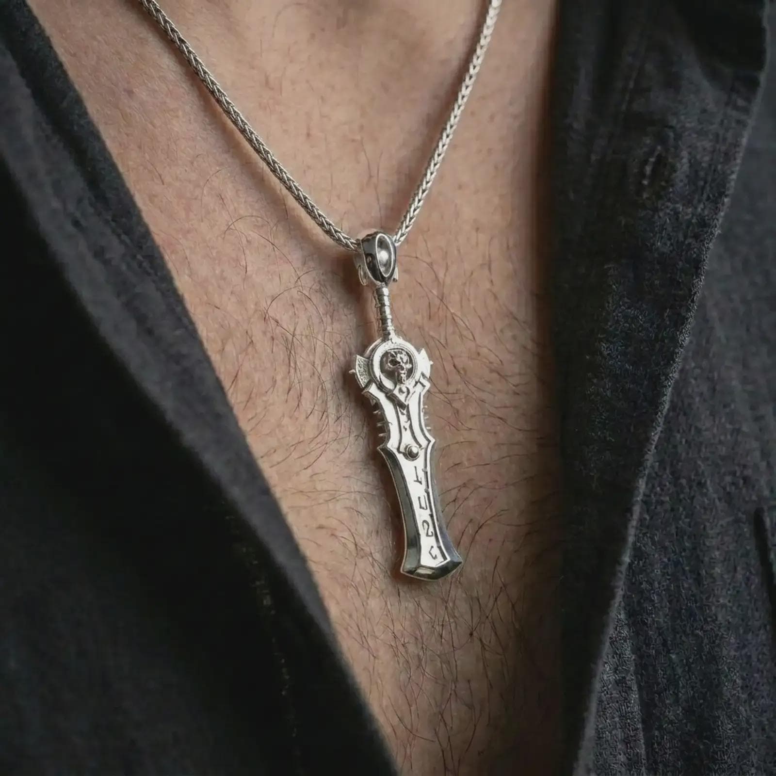 A polished silver demon slayer sword pendant is worn on the neck in a premium close-up lifestyle image, showing the fantasy blade silhouette clearly.