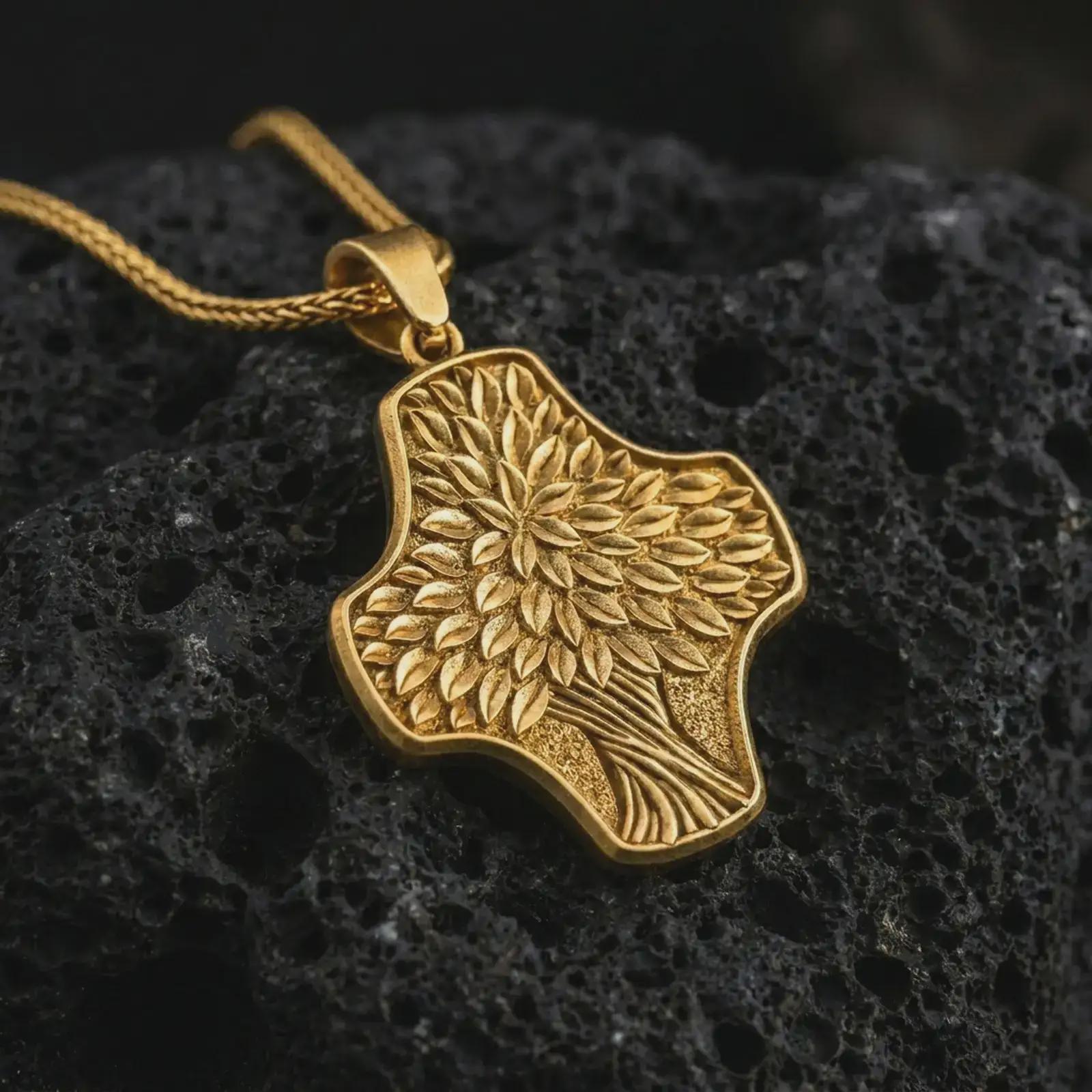 A gold plated Tree of Life cross pendant lies on textured volcanic rock in a dramatic studio macro shot, highlighting the nature-inspired cross design.