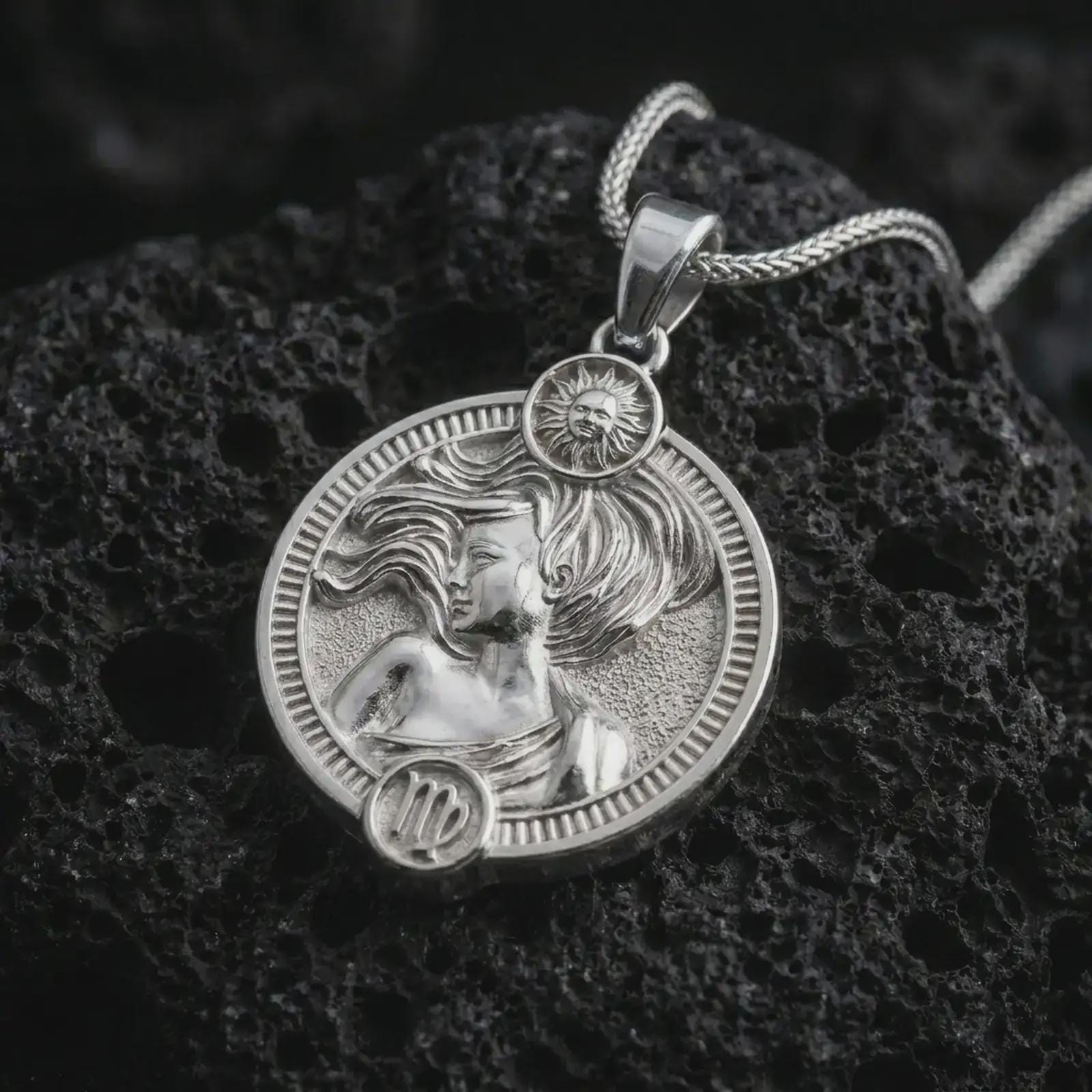 Polished silver Virgo zodiac pendant necklace on textured volcanic rock, centered macro jewelry photo with detailed horoscope figure relief and bright silver highlights.