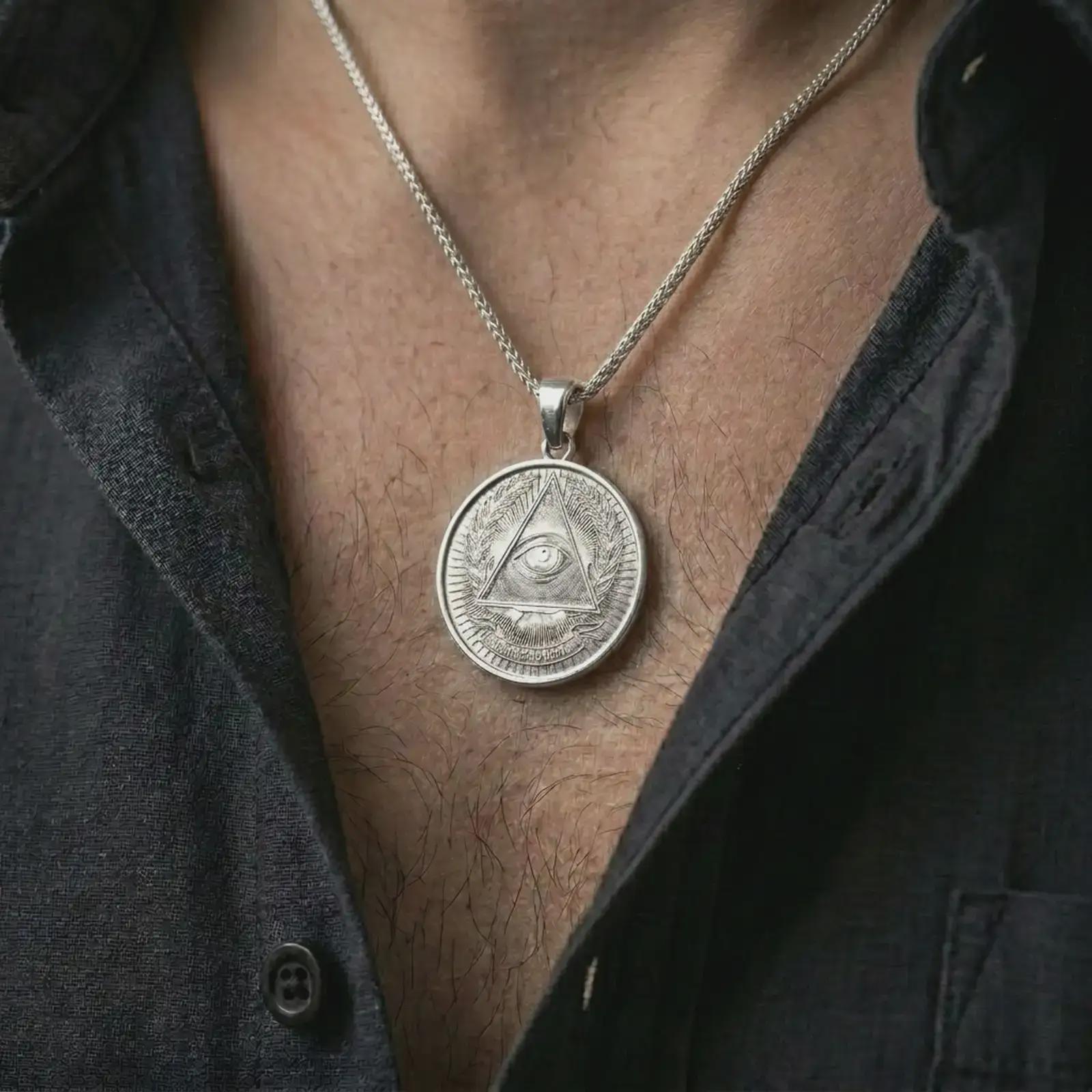 Polished silver all-seeing eye pendant necklace worn on the chest, masculine lifestyle shot highlighting the bright silver finish, triangle eye design, and engraved details.