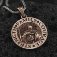 Load image into Gallery viewer, Bronze Spartan warrior pendant necklace on textured volcanic rock, close-up studio shot highlighting the helmeted soldier, spear, shield, strength lettering, and antique silver contrast.
