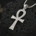 Load image into Gallery viewer, Polished silver ankh cross pendant necklace on textured volcanic rock, centered macro jewelry photo with detailed Egyptian engravings, open loop shape, and bright silver highlights.
