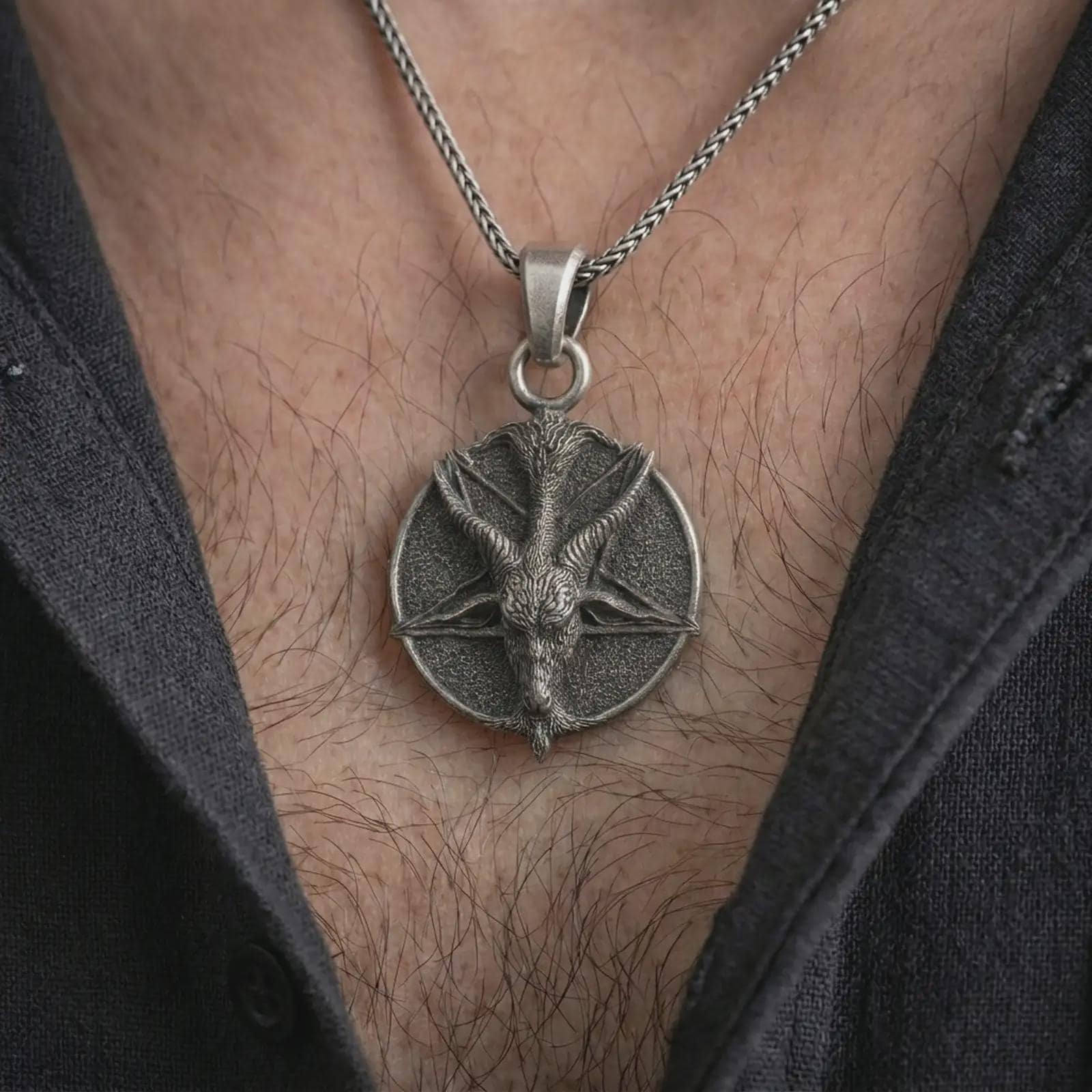 Oxidized goat pentagram pendant necklace worn on the chest, close-up lifestyle jewelry photo showing the gothic goat medallion on a spiga chain with dark clothing.
