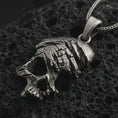 Load image into Gallery viewer, Oxidized cracked skull pendant necklace on textured volcanic rock, close-up studio shot highlighting the fractured skull form, deep cut details, gothic texture, and antique silver contrast.
