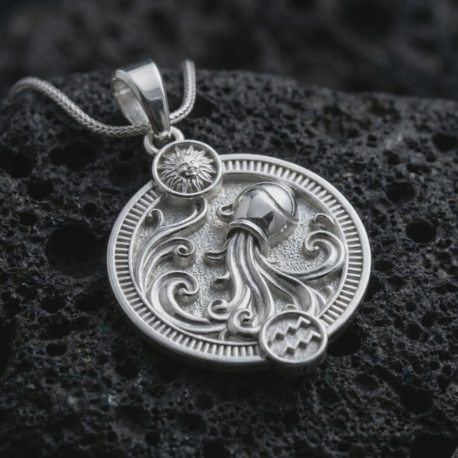 Polished silver Aquarius zodiac pendant necklace on textured volcanic rock, centered macro jewelry photo with detailed water bearer relief and bright silver highlights.