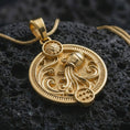 Load image into Gallery viewer, Gold plated Aquarius zodiac pendant necklace on textured volcanic rock, premium close-up studio composition emphasizing the flowing water motif, sun charm, and astrology medallion design.
