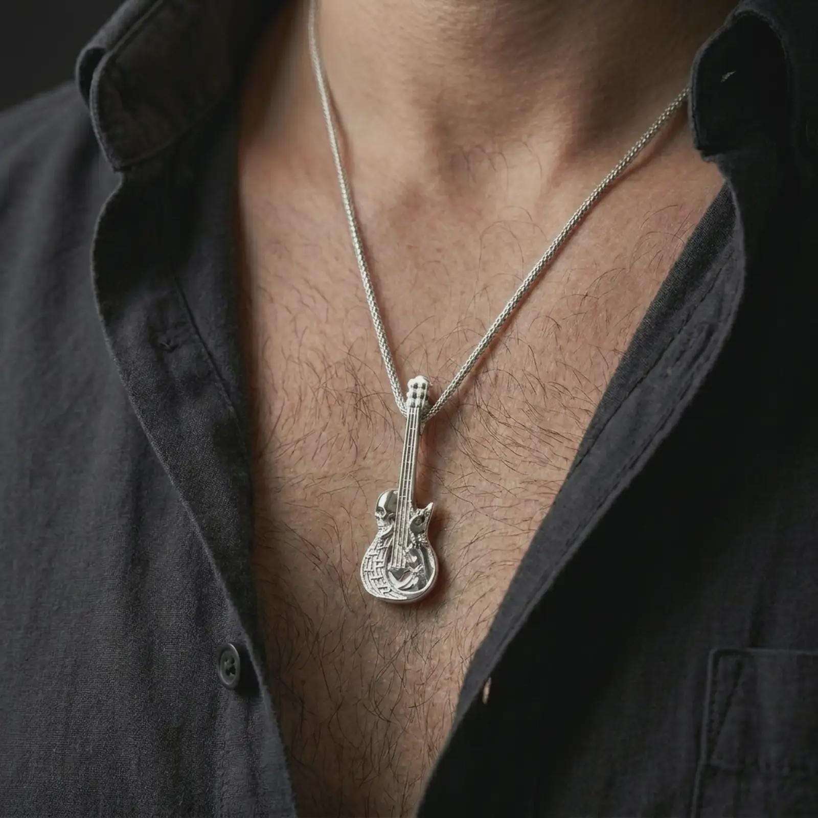 Polished silver skull guitar pendant necklace worn on the chest, masculine lifestyle shot highlighting the guitar strings, skull detail, and bright silver finish.