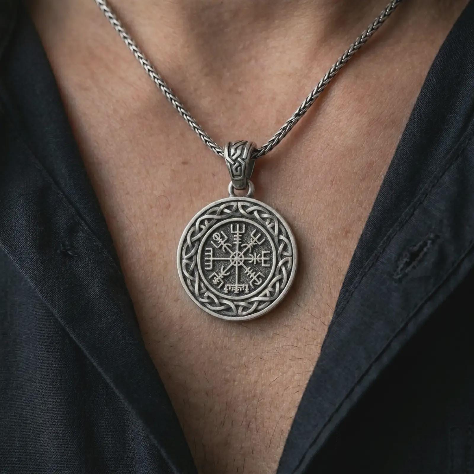Oxidized Vegvisir Viking compass pendant necklace worn on the chest, close-up lifestyle jewelry photo showing the Norse protection medallion on a spiga chain with dark clothing.