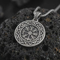 Load image into Gallery viewer, Oxidized Vegvisir Viking compass pendant necklace on textured volcanic rock, close-up studio shot highlighting the Norse protection symbol, Celtic knot border, and antique silver contrast.
