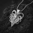 Load image into Gallery viewer, Polished silver biomechanical ram skull pendant necklace on textured volcanic rock, centered macro jewelry photo with detailed horn engraving and bright silver highlights.
