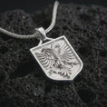 Load image into Gallery viewer, Polished silver double-headed eagle shield pendant necklace on textured volcanic rock, centered macro jewelry photo with detailed feather relief and bright silver highlights.
