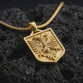 Load image into Gallery viewer, Gold plated double-headed eagle shield pendant necklace on textured volcanic rock, premium close-up studio composition emphasizing the Albanian eagle emblem, bold wings, and heritage crest design.
