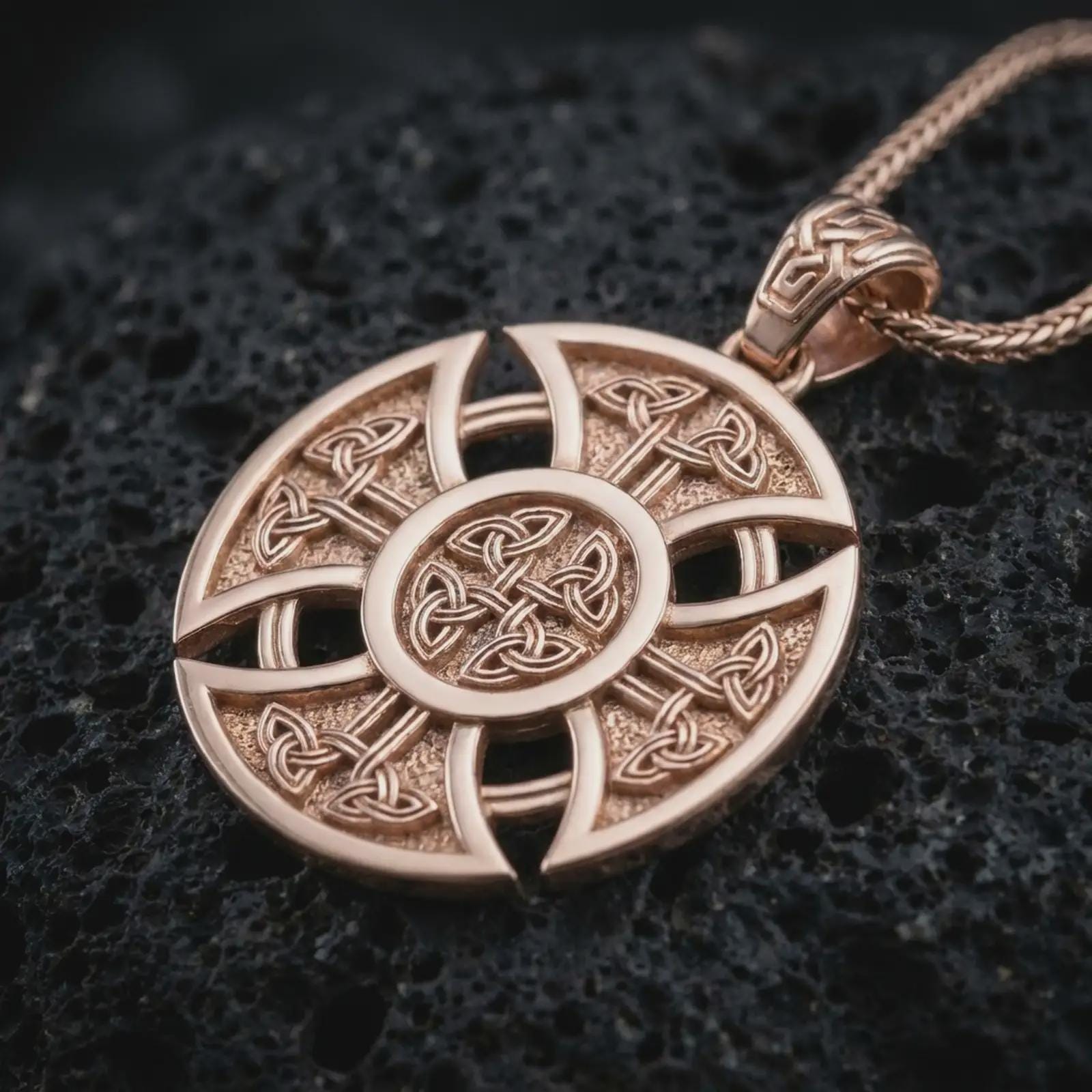 Rose gold plated Celtic cross pendant necklace on textured volcanic rock, detailed macro product shot with soft warm reflections and intricate Celtic knot symbolism.