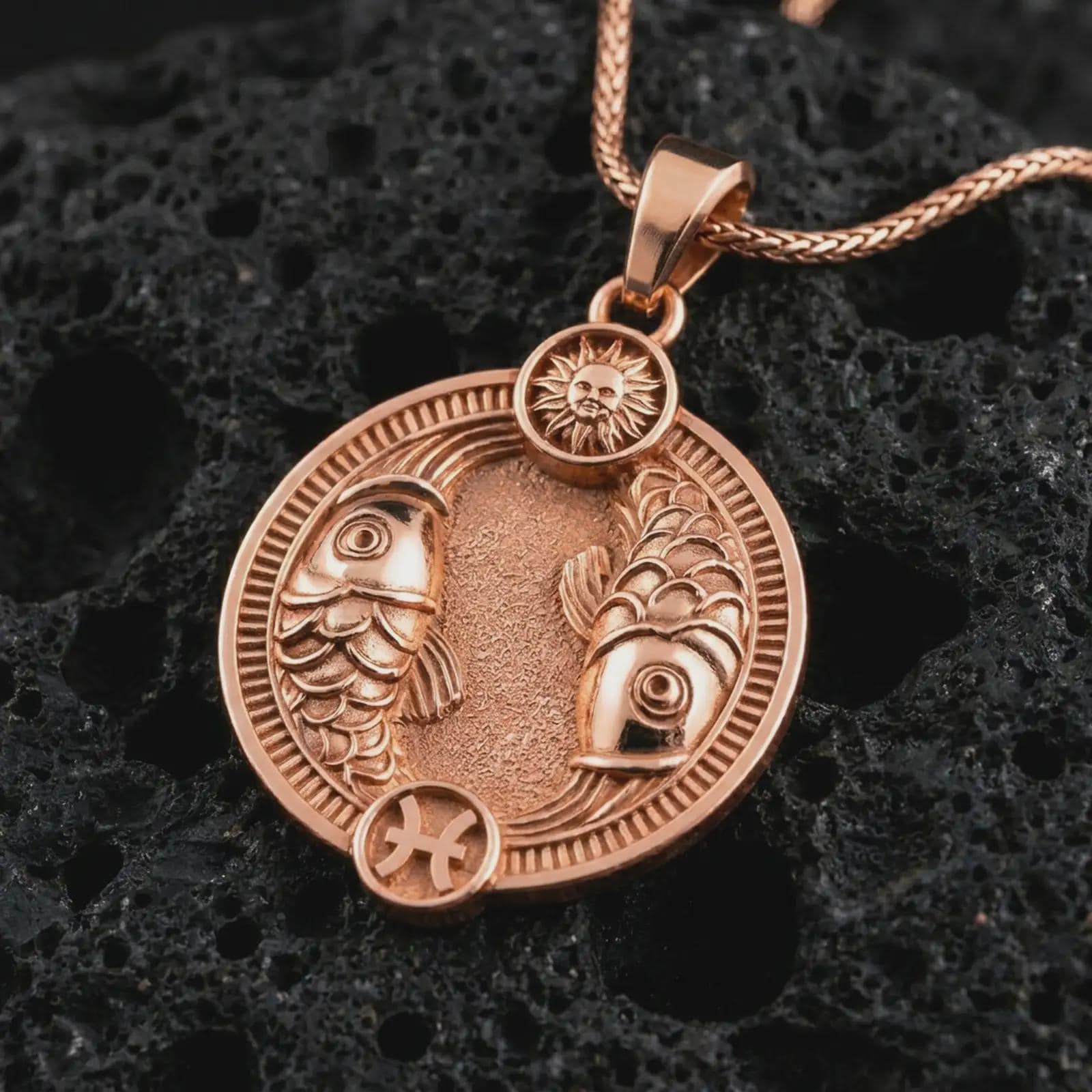 Rose gold plated Pisces zodiac pendant necklace on textured volcanic rock, detailed macro product shot with soft warm reflections and symbolic zodiac styling.