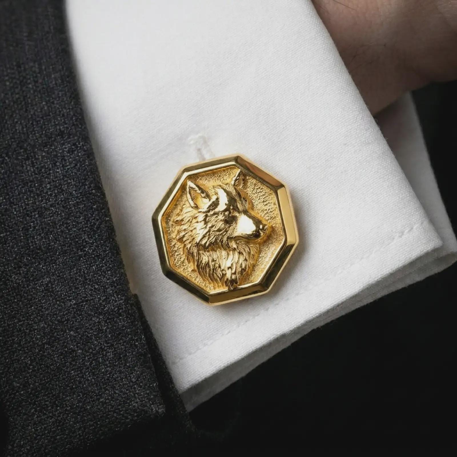 A gold plated wolf head cufflink is worn on a white cuff in a close-up lifestyle shot, styled as a meaningful groomsmen accessory for men.