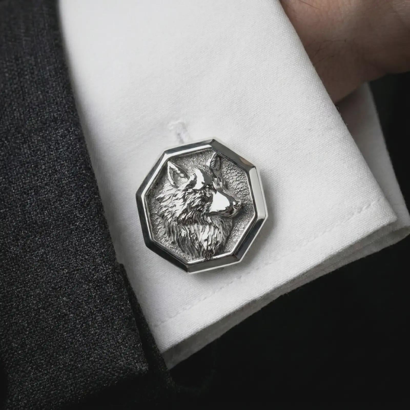 A polished silver wolf head cufflink is worn on a shirt cuff in a premium close-up lifestyle image, showing the detailed wolf profile clearly.