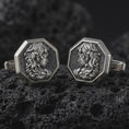 Load image into Gallery viewer, An oxidized Medusa cufflink pair rests on dark volcanic rock in a macro studio close-up, showing a sculpted Gorgon profile inside octagon frames.
