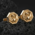 Load image into Gallery viewer, Gold plated scarab cufflinks sit on textured volcanic rock in a dramatic studio macro shot, highlighting the Egyptian winged beetle motif and formal accessory design.
