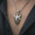 Load image into Gallery viewer, A polished silver Loki pendant is worn on the neck in a premium close-up lifestyle image, showing the faceted horned mask clearly.
