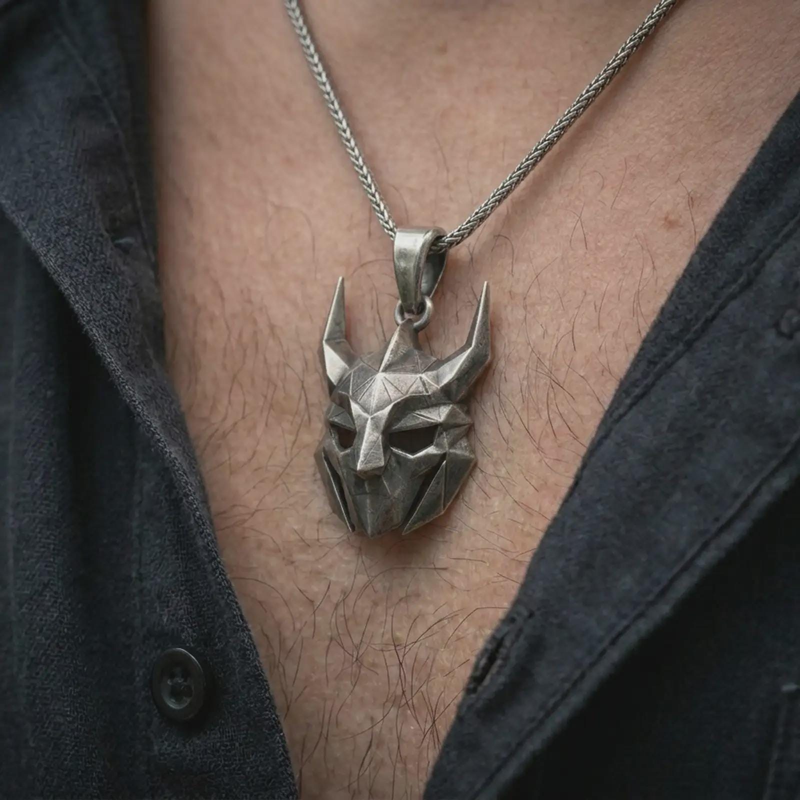 An oxidized Loki pendant is worn on the neck in a close-up lifestyle shot, centered on the chest as a bold Norse trickster symbol.