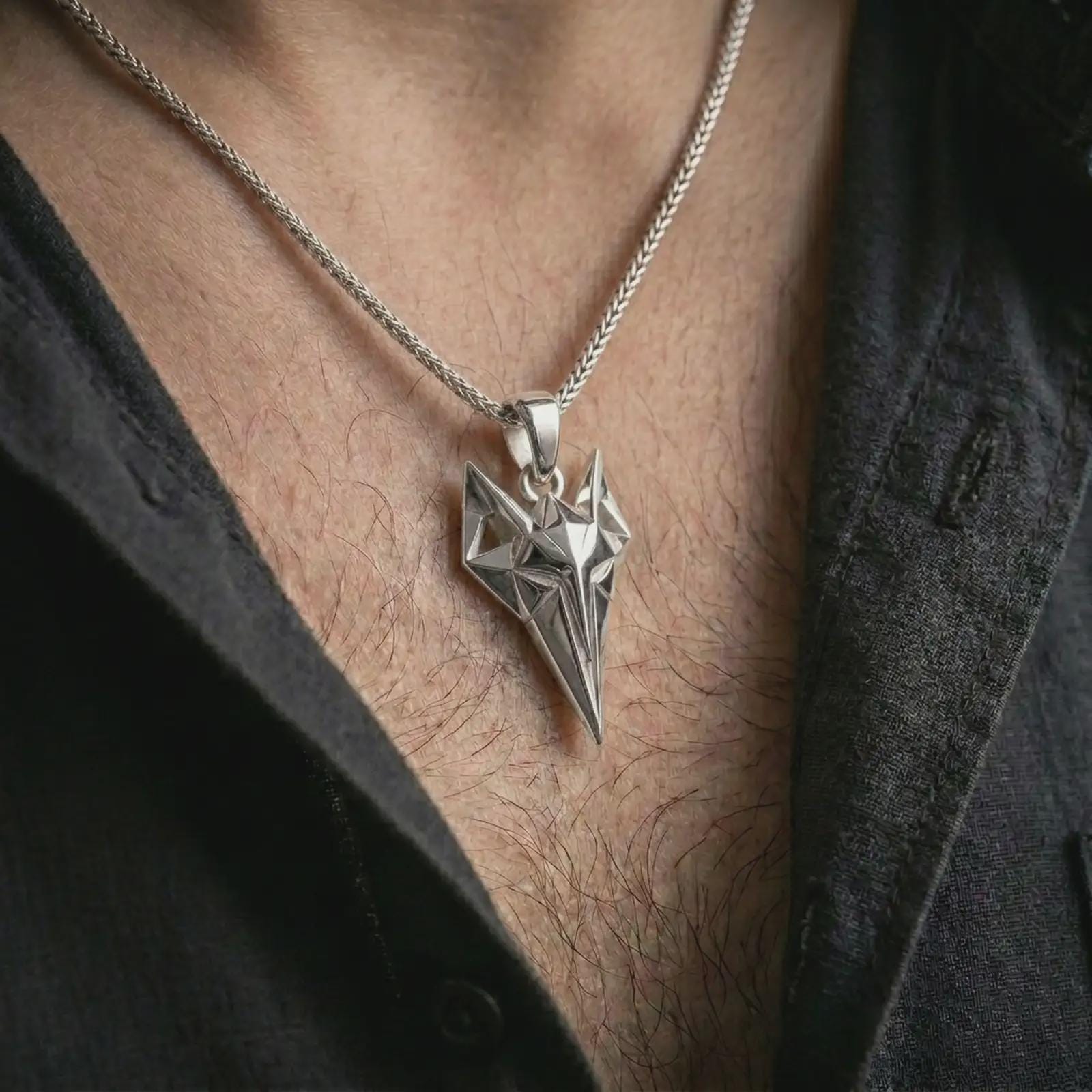 A polished silver Freyja cat pendant is worn on the neck in a premium close-up lifestyle image, showing the faceted feline symbol clearly.