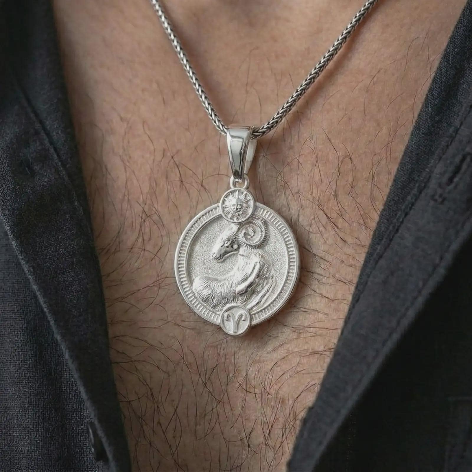 Polished silver Aries zodiac pendant necklace worn on the chest, masculine lifestyle shot highlighting the ram relief, sun detail, and bright silver finish.
