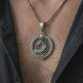 Load image into Gallery viewer, Oxidized Aries zodiac pendant necklace worn on the chest, close-up lifestyle jewelry photo showing the ram astrology medallion on a spiga chain with dark clothing.
