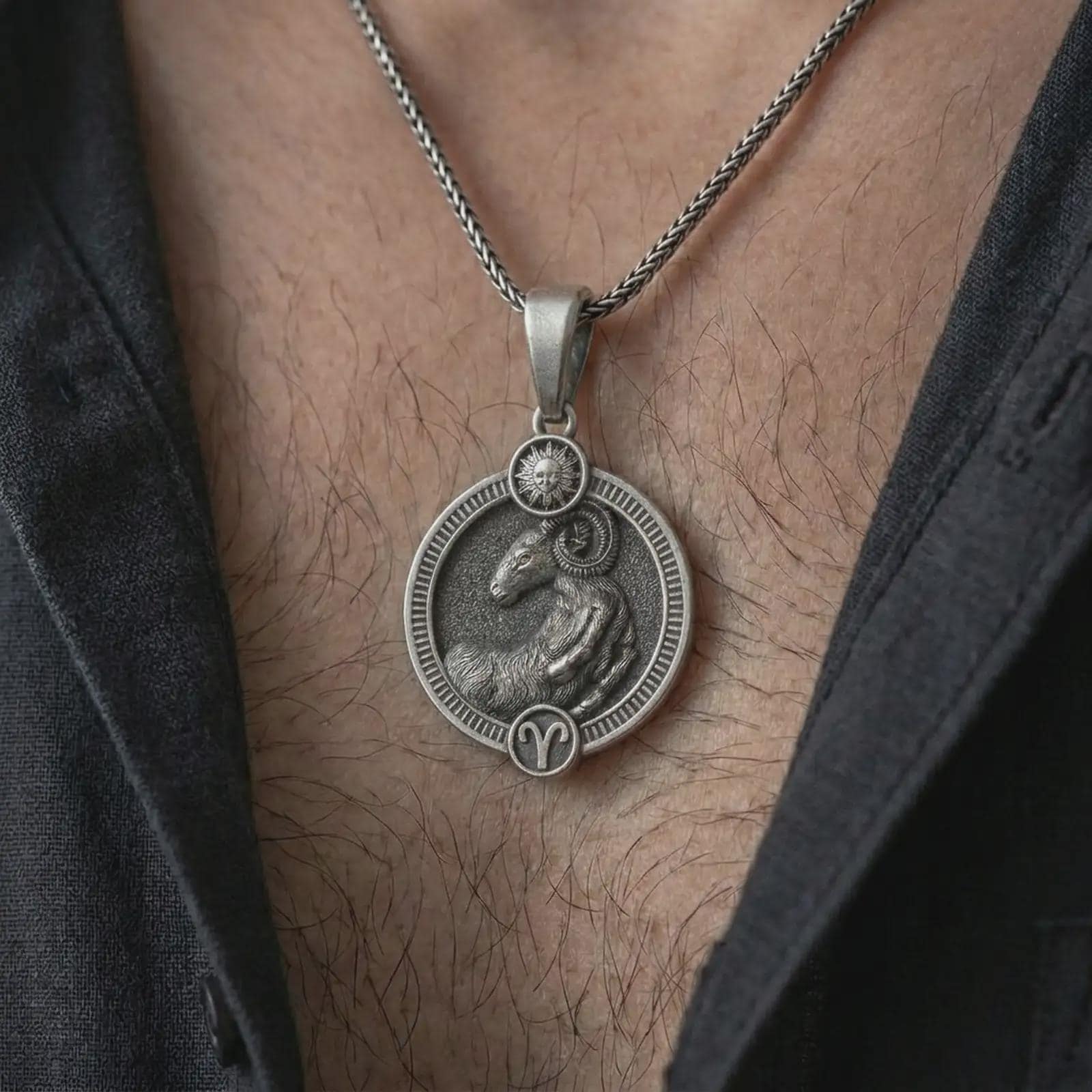 Oxidized Aries zodiac pendant necklace worn on the chest, close-up lifestyle jewelry photo showing the ram astrology medallion on a spiga chain with dark clothing.