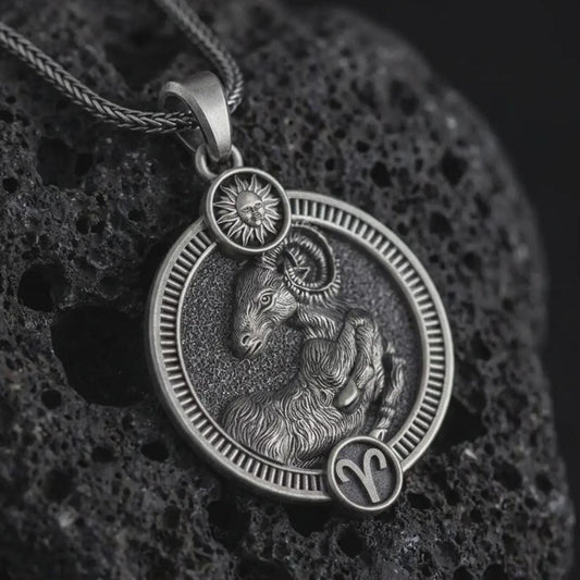 Oxidized Aries zodiac pendant necklace on textured volcanic rock, close-up studio shot highlighting the ram relief, sun detail, Aries symbol, and antique silver contrast.