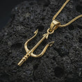 Load image into Gallery viewer, Gold plated Poseidon trident pendant necklace on textured volcanic rock, premium close-up studio composition emphasizing the Greek mythology trident, sculpted prongs, and bold pendant silhouette.
