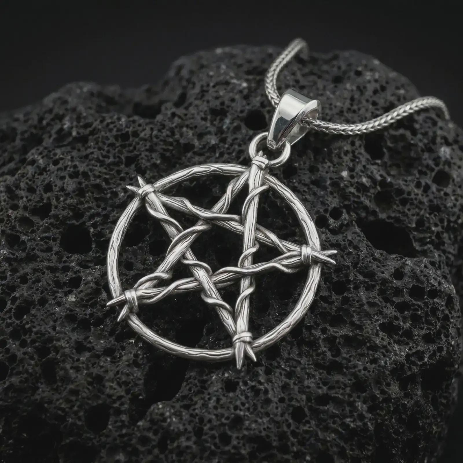 Polished silver thorn pentagram pendant necklace on textured volcanic rock, centered macro jewelry photo with detailed branch-like texture and bright silver highlights.
