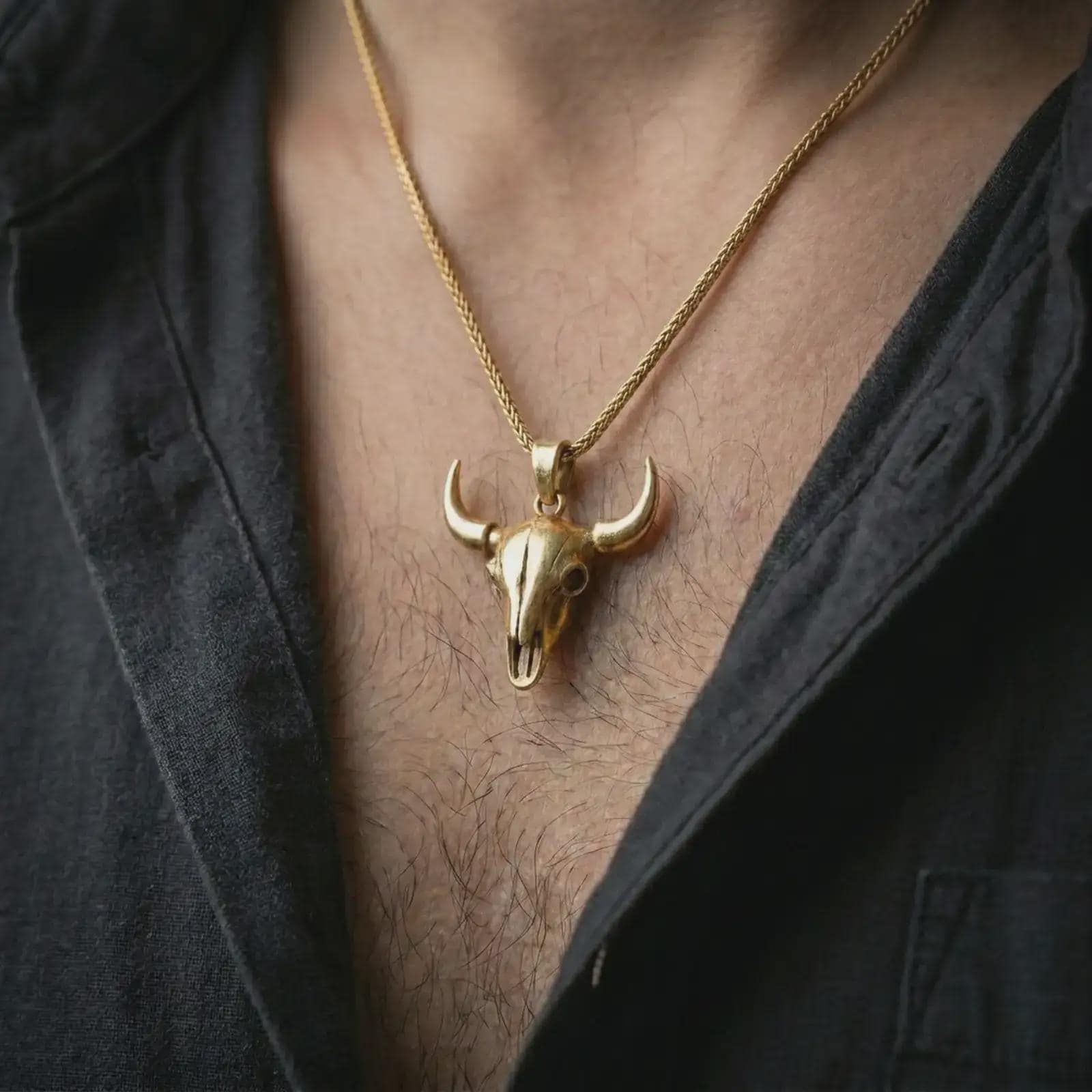 Gold plated bull skull pendant necklace worn on the chest, premium lifestyle jewelry photo with the western bull skull pendant centered on a spiga chain.