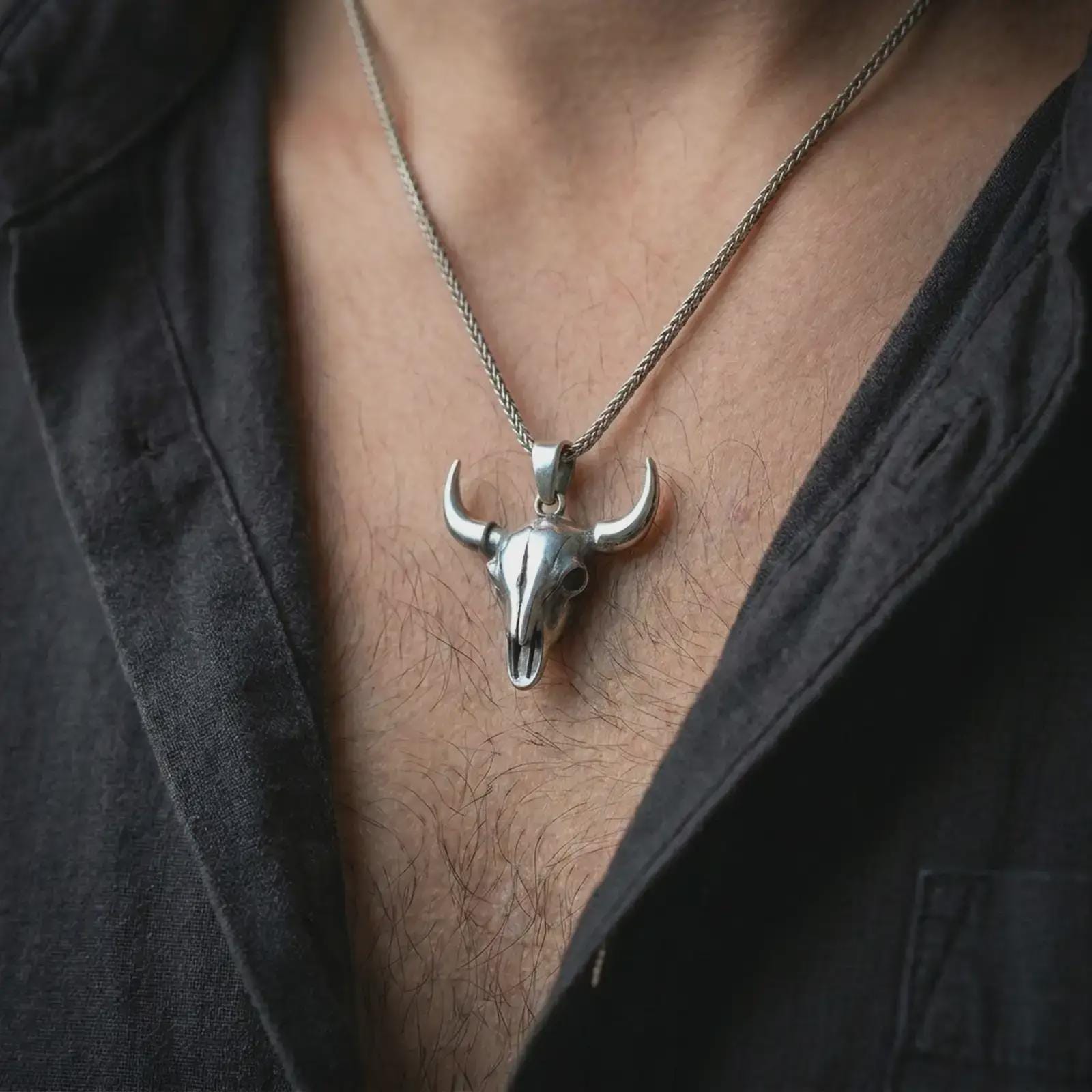 Polished silver bull skull pendant necklace worn on the chest, masculine lifestyle shot highlighting the bright silver finish, long horns, and sculpted skull detail.
