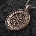 Load image into Gallery viewer, Bronze Vegvisir Viking rune pendant necklace on textured volcanic rock, close-up studio shot highlighting the Norse compass symbol, rune border, rope frame, and antique silver contrast.
