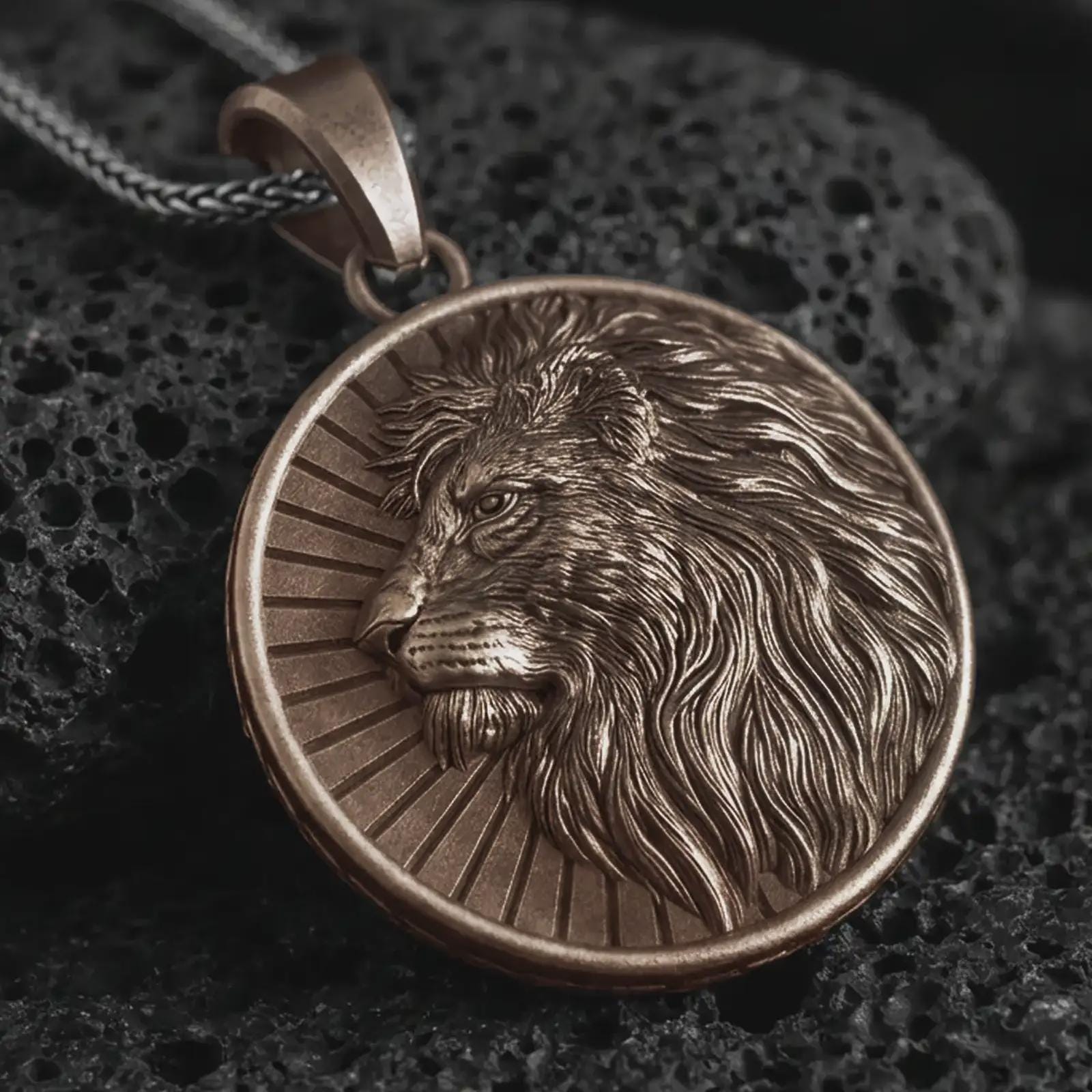 Bronze Lion of Judah pendant necklace on textured volcanic rock, close-up studio shot highlighting the lion profile, flowing mane, sunburst background, and antique silver contrast.