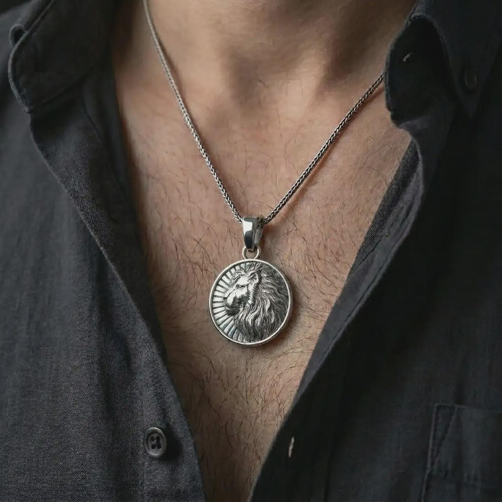 Polished silver Lion of Judah pendant necklace worn on the chest, masculine lifestyle shot highlighting the bright silver finish, detailed mane texture, and sunburst relief.