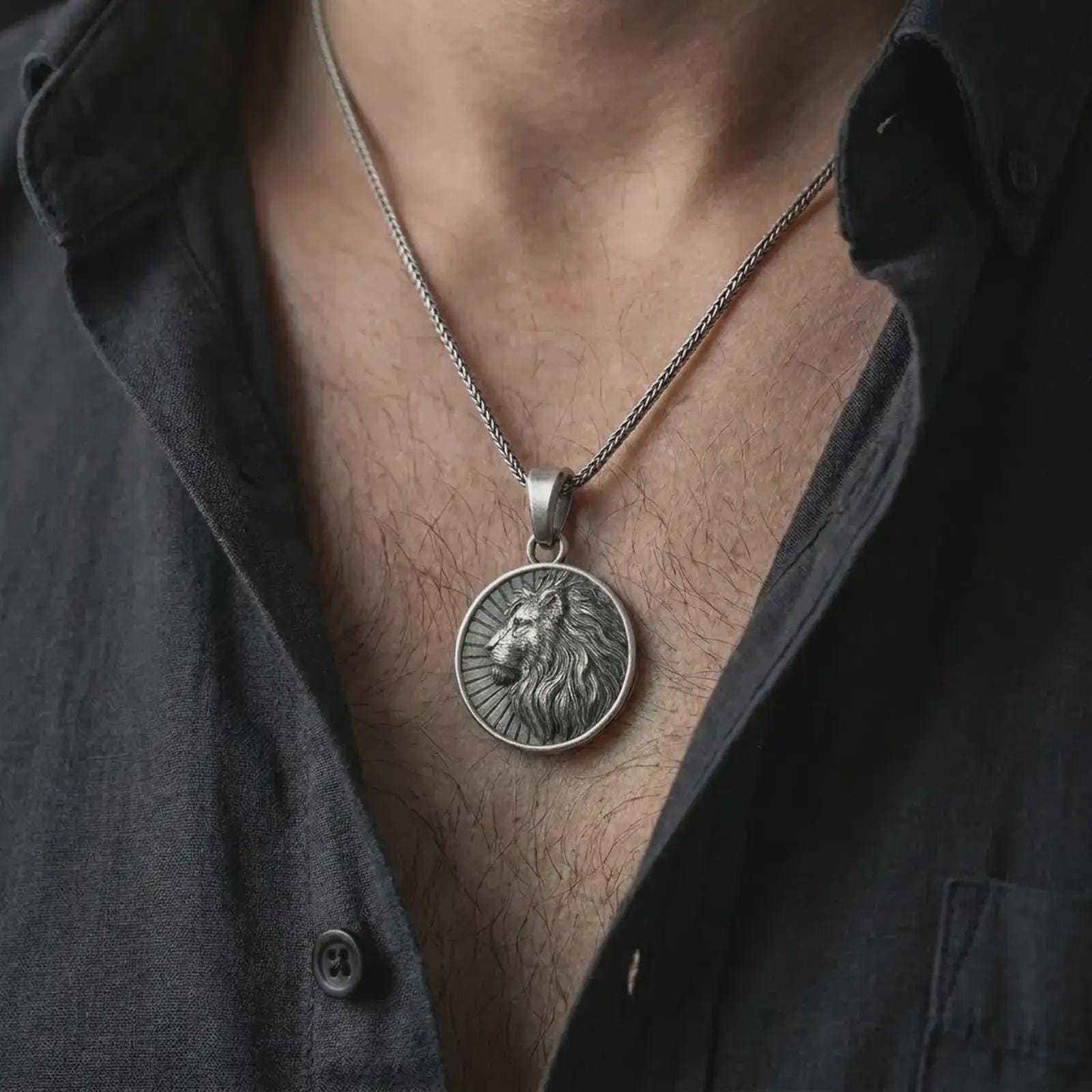 Oxidized Lion of Judah pendant necklace worn on the chest, close-up lifestyle jewelry photo showing the lion medallion on a spiga chain with dark clothing.