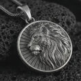 Load image into Gallery viewer, Oxidized Lion of Judah pendant necklace on textured volcanic rock, close-up studio shot highlighting the lion profile, flowing mane, sunburst background, and antique silver contrast.
