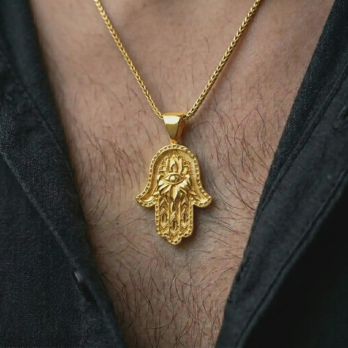Gold plated hamsa hand pendant necklace worn on the chest, premium lifestyle jewelry photo with the hamsa evil eye pendant centered on a spiga chain.