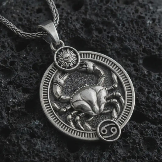 Oxidized Cancer zodiac pendant necklace on textured volcanic rock, close-up studio shot highlighting the crab relief, sun detail, Cancer symbol, and antique silver contrast.