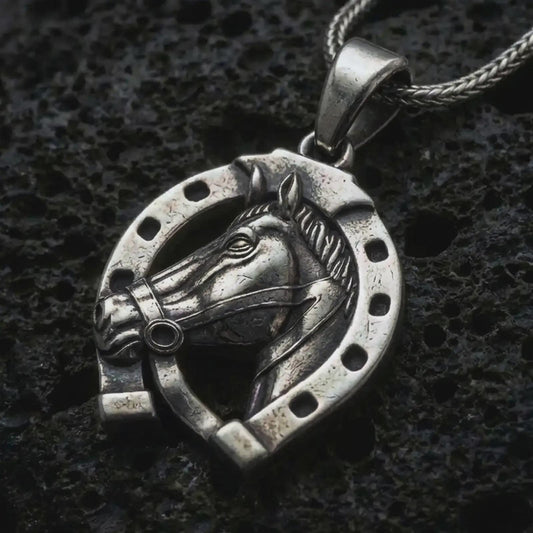 Oxidized horseshoe pendant necklace on textured volcanic rock, close-up studio shot highlighting the horse head relief, lucky horseshoe frame, openwork design, and antique silver contrast.