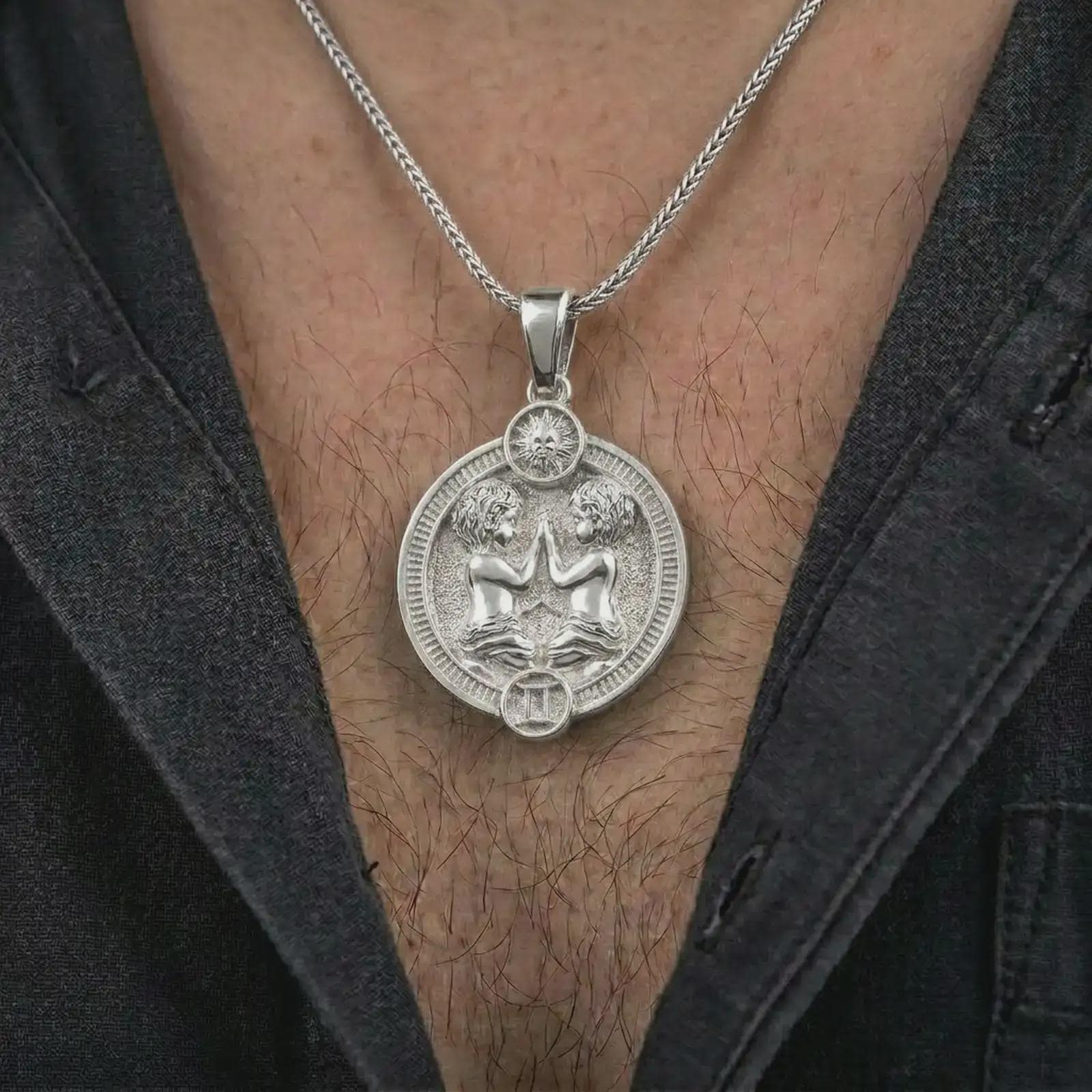 Polished silver Gemini zodiac pendant necklace worn on the chest, masculine lifestyle shot highlighting the twin figures, sun detail, and bright silver finish.