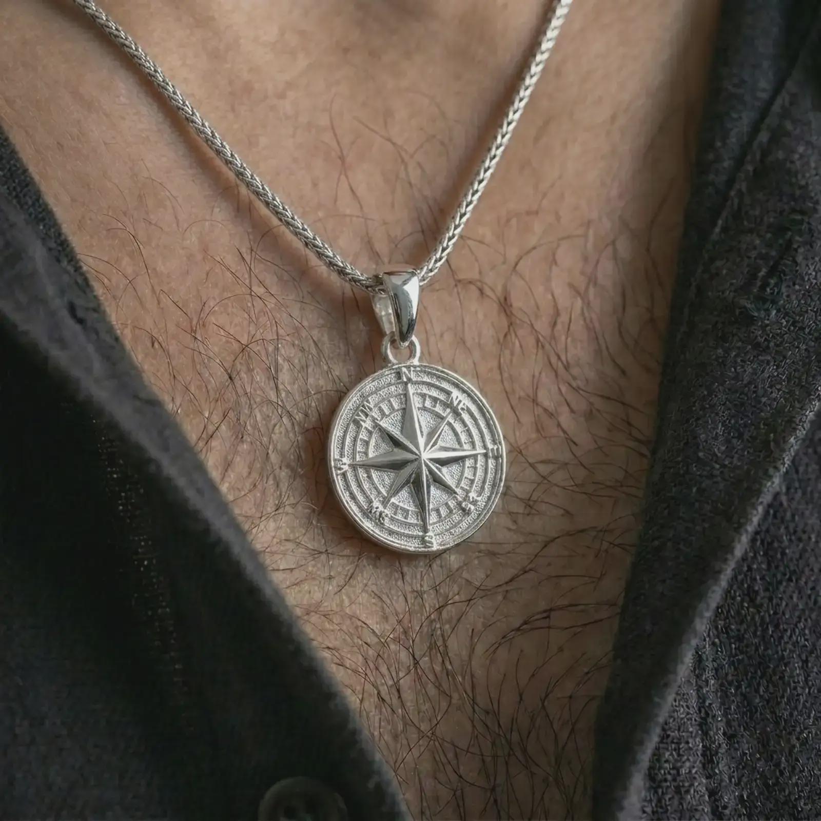 Polished silver compass rose pendant necklace worn on the chest, masculine lifestyle shot highlighting the bright silver finish, directional star, and engraved compass letters.
